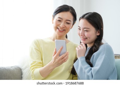 Asian Mother And Daughter Using Smart Phone In The Living Room