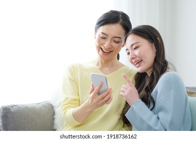 Asian Mother And Daughter Using Smart Phone In The Living Room