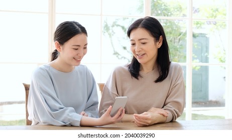 Asian Mother And Daughter Using Smart Phone At Home