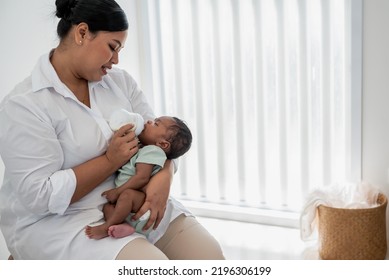 Asian Mother Feeding Milk From Bottle Milk To Her 1-month-old Baby Black Skin Newborn Son, Is Half-Nigerian Half-Thai, To Family And Food For Infant Concept.