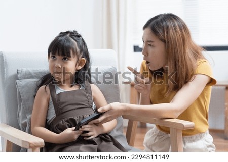 Asian mother grab mobile phone from her daughter for stop her daughter from game addiction.