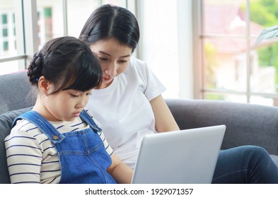 Asian mother happily sat teaching her daughter, reading and doing homework. stay at home on vacation And young people working on homework Concept Social Distancing the COVID -19
