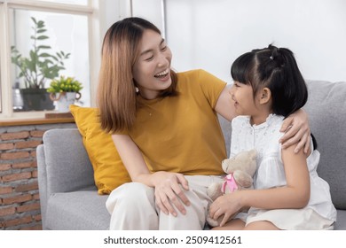 Asian mother having a good time chatting with her daughter on the couch - Powered by Shutterstock