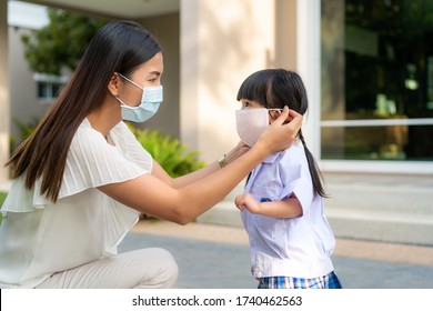 Asian mother help her daughter wearing medical mask for protection Covid-19 or coronavirus outbreak in village park to prepare go to school when back to school order. - Powered by Shutterstock