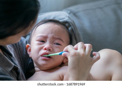 Asian Mother Is Helping To Brush Teeth For Her Baby Crying Unhappy When Brushing Teeth,Concept Take Care Dental Health.