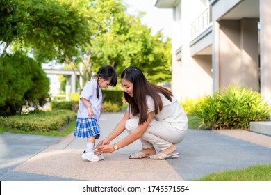 Asian mother helping her daughter put shoes on or take off at outdoor park getting ready to go out together or coming back home from school in happy family with kids concept.
 - Powered by Shutterstock