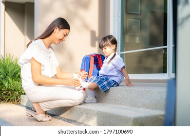 Asian mother helping her daughter put shoes on or take off at outdoor park getting ready to go out together or coming back home from school in happy family with kids concept.
 - Powered by Shutterstock