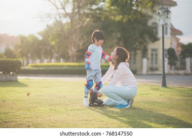 Asian mother helping her son putting his roller skates on enjoying time together in the park - Powered by Shutterstock