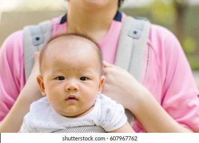 Asian Mother And Her Baby Girl In A Baby Carrier, Outdoors Portrait