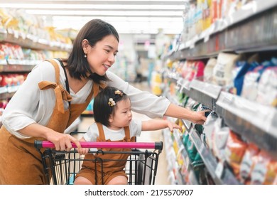 Asian Mother And Her Daughter Buying Food At Huge Supermarket , Baby Sit In Trolley, Family Shopping Concept.