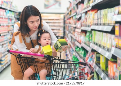 Asian Mother And Her Daughter Buying Food At Huge Supermarket , Baby Sit In Trolley, Family Shopping Concept.