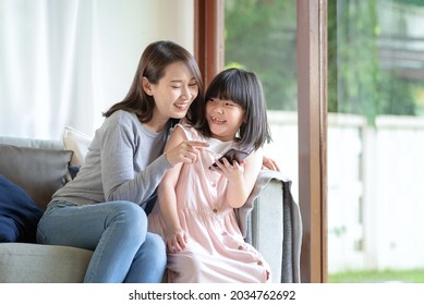 Asian Mother And Her Daughter Enjoy Using Internet Via Smart Phone At Home 