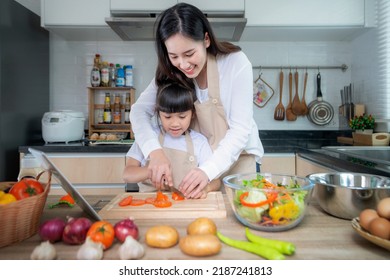 Asian mother and her daughter enjoy cooking togather at home kitchen for cooking education and prepare food for dinner at home - Powered by Shutterstock