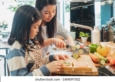 Asian Mother And Her Daughter Kid Cooking Food For Breakfast In Kitchen