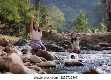 Asian mother and her daughter playing splash water on the river together with fun. Outdoor activity for family on vacation. - Shutterstock ID 2253713567