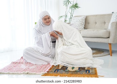 An Asian mother and her daughter praying together. Home.