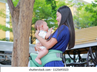 Asian Mother With Her Infant On Ergonomic Baby Carrier.