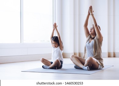 Asiatische Mutter und ihre Tochter, die zu Hause Stretchübung ausüben