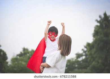 Asian Mother And Her Son Playing Together In The Park,Boy In Superhero's Costume.