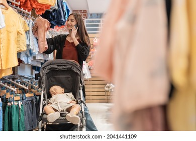 Asian Mother With Her Son Shopping In The Mall While Calling On Phone