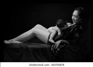 Asian Mother Holding Her Laying Down Baby On Her Body And Breast Feeding Baby In Black And White Color