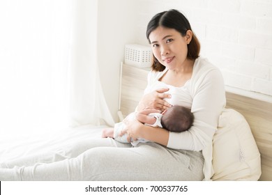 Asian Mother Holding Her Newborn Baby Boy And Breastfeeding, Milk Mother For Child Concept