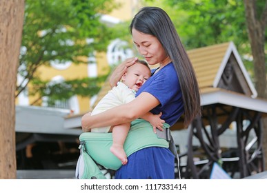 Asian Mother Hugging Her Infant On Ergonomic Baby Carrier.