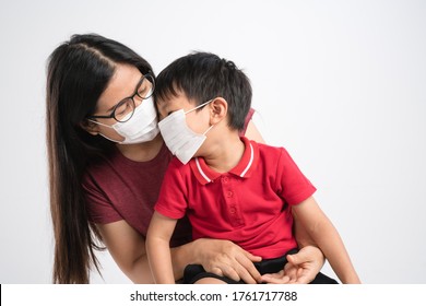 Asian mother hugging her son while wearing medical masks for preventing corona virus or covid-19 - Powered by Shutterstock