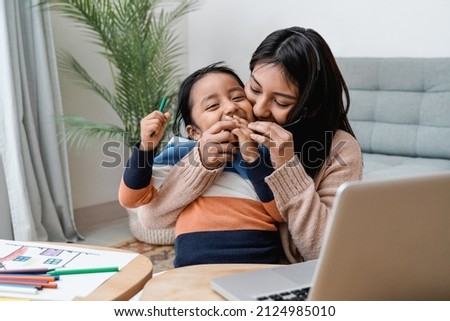 Asian mother and kid having fun together while working at home - Family love concept - Focus on mom face