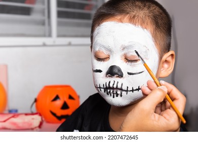 Asian Mother And Kid Son Getting Makeup Halloween Face Painting Look Like Ghost, Portrait Of Woman Applying Color Brush To Child Face For Party, Happy Halloween Day Concept