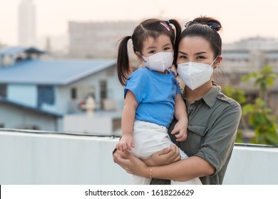 Asian Mother And Little Young Daughter Wearing Mask For Prevent Dusk Pm 2.5 Bad Air Pollution On Deck In Bangkok City Thailand 2020. 