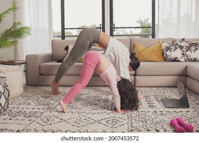 Asian Mother And Mixed Race Daughter Exercising Yoga Online Virtual Streaming Lesson At Home During Covid Pandemic, Family Remote Learning Together, Health Care, Healthy Lifestyle Concept