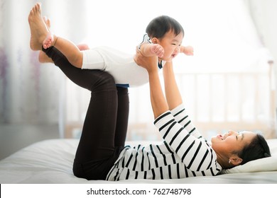 Asian Mother Play With Her Baby On The Bed,  Mother, Kid, Home, Baby And Family Concept