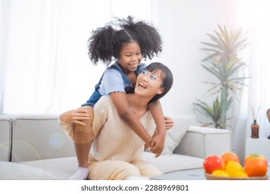 Asian mother play with her kid while she try to climb up over her mom shoulder with smile of happyness, relationship of parent and child in family. mother's day concept. - Powered by Shutterstock