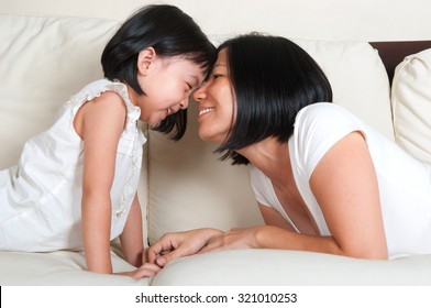 Asian Mother Playing With Daughter On The Sofa