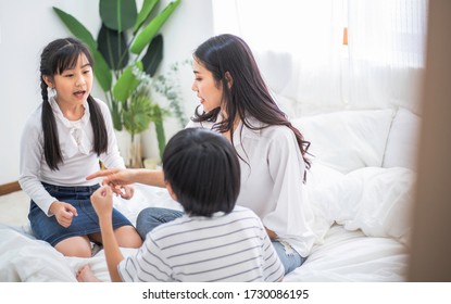 Asian Mother Playing With Two Kids In Bedroom At Home. Mom Parenting Son And Daughter. Sister Brother Learning Lesson Together. Happy Family Living Insurance. Quarantine During Coronavirus Or Covid-19
