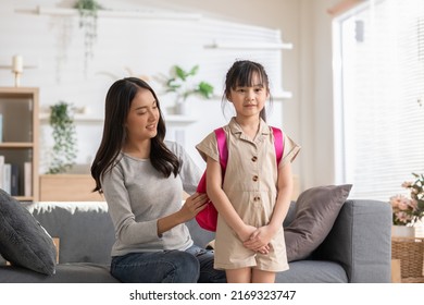 Asian mother preparing school bag of her daughter ready to school in morning. Happy mom helping her little girl get ready for school with love. First day to school. Good moment family.