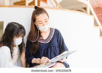 Asian Mother Reading Book With Her Children Kid Lying On Floor At Home During Covid19 Stay Home.Mom Telling Story To Her Child At Kids Club.medical Mask.study Bible At Home,Teacher Family Activities