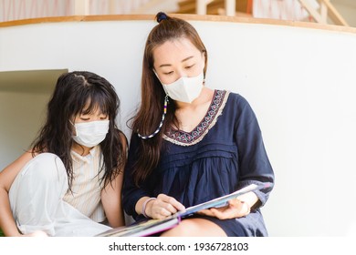 Asian Mother Reading Book With Her Children Kid Lying On Floor At Home During Covid19 Stay Home.Mom Telling Story To Her Child At Kids Club.medical Mask.study Bible At Home,Teacher Family Activities