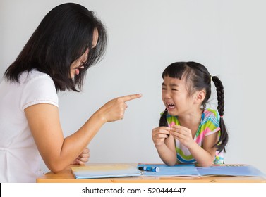 asian mother is scolding her daughter and the girl cry