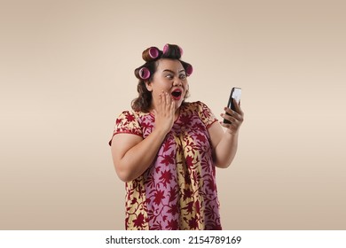 An Asian Mother With Shocked Expression Looking Her Phone. She Is Doing Online Shopping Through Her Mobile Phone. 