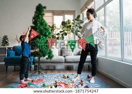 Asian mother and son decorate the living room for Christmas
