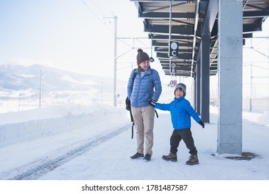 Asian mother and son waiting express train on railway station platform,winter travel concept