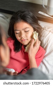 Asian Mother Take Cool Towel For Reduce High Fever On Sick Girl Forehead On Bed At Morning Time, Selective Focus, Healthy And Infection Concept