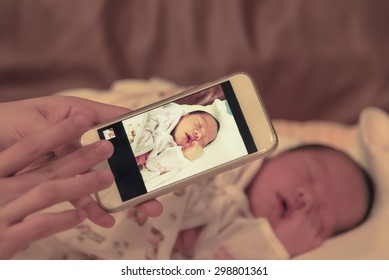 Asian mother take a photo of her baby female son with smart phone focused on the device  - Powered by Shutterstock