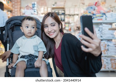 Asian Mother Take Selfie With Her Son While Shopping In The Mall