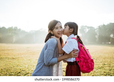 asian mother taking her daughter to school in the morning, kissing and embrace before leaving