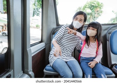 asian mother taking her daughter to school by riding bus public transport wearing a face mask - Powered by Shutterstock