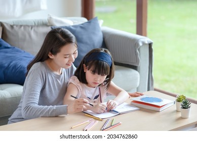 Asian Mother Teaching Her Cute Kid Daughter To Studying In Living Room At Home