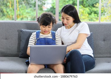 Asian Mother Teaching Her Daughter To Learn From Online Class Using Laptop For Homeschooling And Education Concept